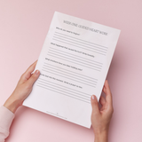 Hand holding a worksheet titled 'Week One Guided Heart Work' on a pink background